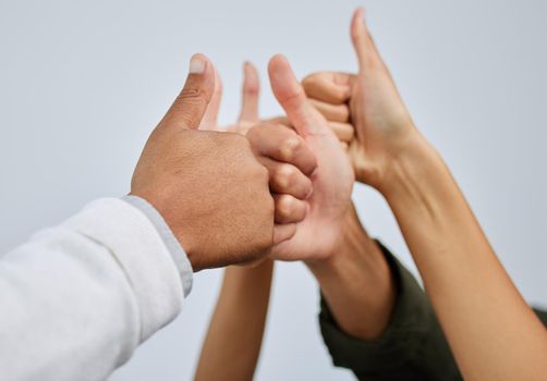 Now thats something we all agree on. Closeup shot of a group of people showing thumbs up together against a white background.