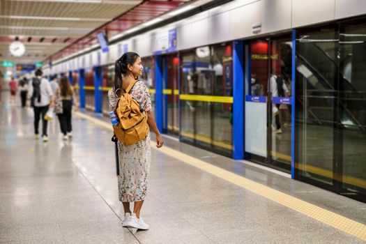 Asian woman tourist waiting for skytrain at railway station platform in the city Bangkok Thailand
