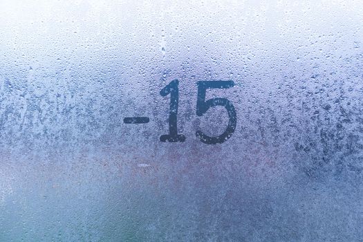 Handwritten temperature on a foggy window. 15 degrees below zero. Cold and frosty weather concept