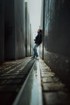 May 2022 - Berlin, Germany. Woman stands in dark maze between tall blocks in Holocaust Jewish Memorial of Murdered Jews. Light at the end of tunnel.