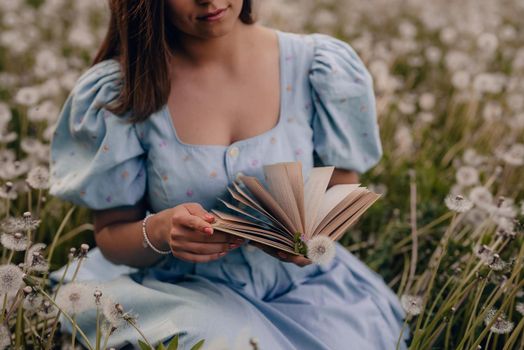 Woman flips through pages of paper book. Lady in retro or vintage dress reading interesting novel while sitting on nature. Atmospheric scene. Education, hobby, entertainment concept.