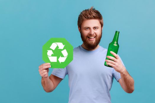 Man in T-shirt holding glass bottle and recycling green symbol, sorting his rubbish, saving ecology.