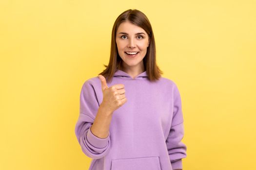 Woman looking at camera with toothy smile and showing thumb up, approval sign satisfied with service