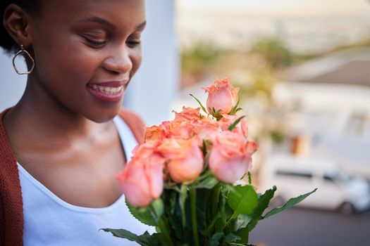 These smell amazing. an attractive young woman standing alone at home and holding a bouquet of roses.