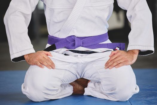 Showing respect to the sport. an unrecognizable young man kneeling in full jiu jitsu gi in the gym.