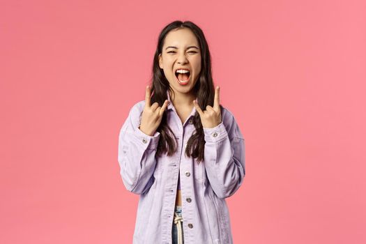 This festival rocks. Enthusiastic, excited good-looking girl having fun on awesome concert, show rock-n-roll heavy metal sign screaming from joy and thrill, standing pink background