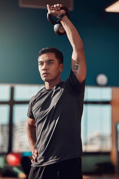 Make those biceps pop. a young man working out using a kettlebell in the gym.