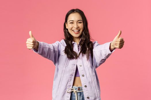 Totally agree. Portrait of cheerful young woman in denim jacket approve awesome, super cool idea, show thumbs-up and smiling happy, cheering, rooting or encourage do it, like plan, pink background