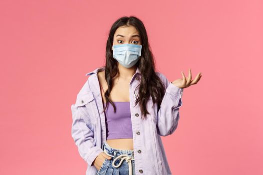Covid19, quarantine, people concept. Surprised young woman in medical face mask stay safe during coronavirus pandemia outbreak, look ambushed wear medical mask, raise hand in amazement