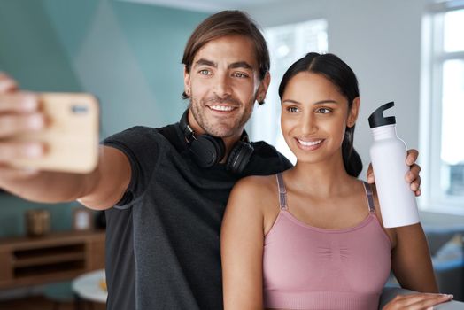 Were workout ready. an athletic young couple taking selfies before starting their workout at home.