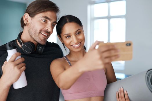 Lets tale a selfie before we get all sweaty. an athletic young couple taking selfies before starting their workout at home.