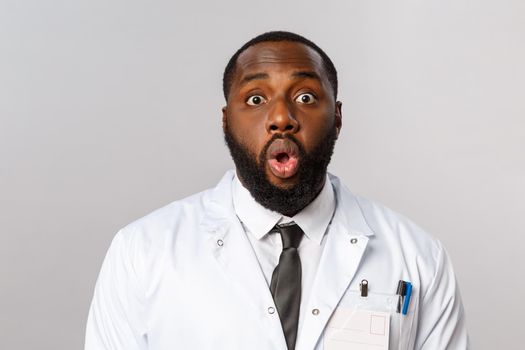 Healthcare, medicine and hospital treatment concept. Close-up portrait of shocked and speechless african-american doctor, physician gasp and startled staring camera, standing astonished
