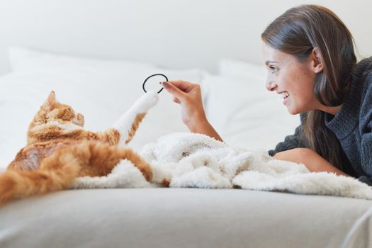 Regular play with your furry feline is so important. a young woman playing with her cat at home.