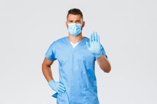 Healthcare workers, covid-19, coronavirus and preventing virus concept. Serious-looking professional doctor, nurse in scrubs, give restriction, prohibit using antibiotics, show stop sign