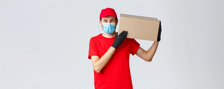 Packages and parcels delivery, covid-19 quarantine delivery, transfer orders. Friendly courier bring order to client house, holding package box on shoulder, wear face mask and rubber gloves