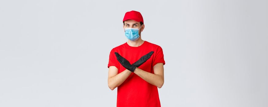 Covid-19, self-quarantine, online shopping and shipping concept. Courier disapprove contact during shipping goods, refuse or rejecting work without face mask and gloves, make cross sign