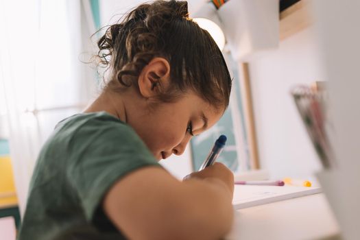 little girl writes concentrated at the desk