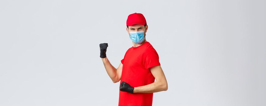 Covid-19, self-quarantine, online shopping and shipping concept. Energized, excited delivery guy do champion dance, fist pump and looking empowered, celebrate success, rejoicing in courier outfit