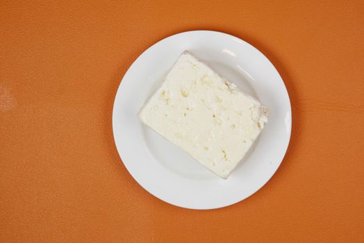 feta cheese on a plate on orange background