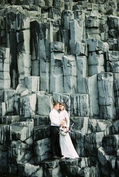 Bride and groom stand on the black rocks of Vik beach in Iceland