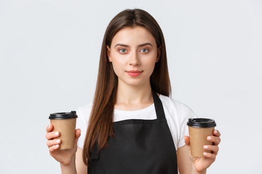 Employees, job employment, small business and coffee shop concept. Close-up of smiling friendly-looking female barista, cafe employee handling two cups of coffee order to client