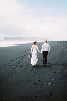 Bride and groom walk on the black sand. Vik Beach, Iceland