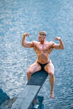 male bodybuilder by the water in nature