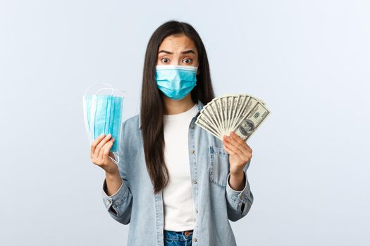 covid-19 pandemic, coronavirus expences and finance concept. Concerned and complicated distressed asian girl pay lots of money for medical mask that are expensive, cant afford respirators