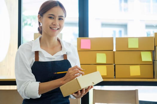 Asian businesswoman Start up small business owner writing address on cardboard box a.