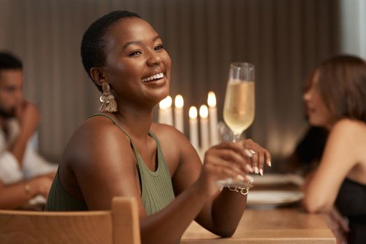 This good mood was sponsored by bubbly. an attractive young woman sitting with her friends during a dinner party and enjoying a glass of champagne.