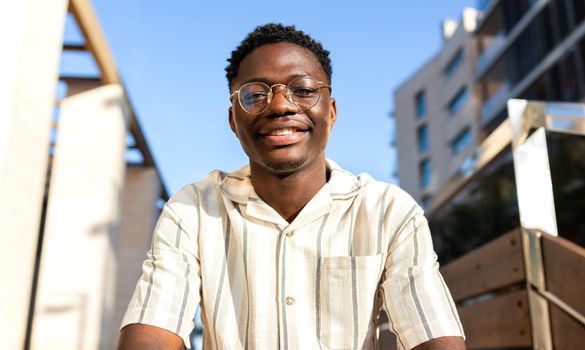 Smiling young black man outdoors looking at camera.