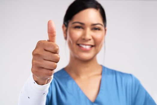 Im a force of God. Portrait of a young doctor showing a thumbs up sign against a white background.