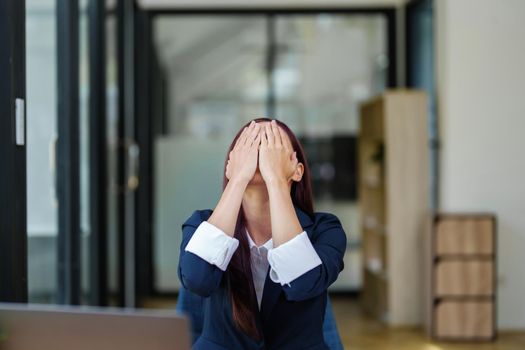 Portrait of an Asian businesswoman showing a headache from depression