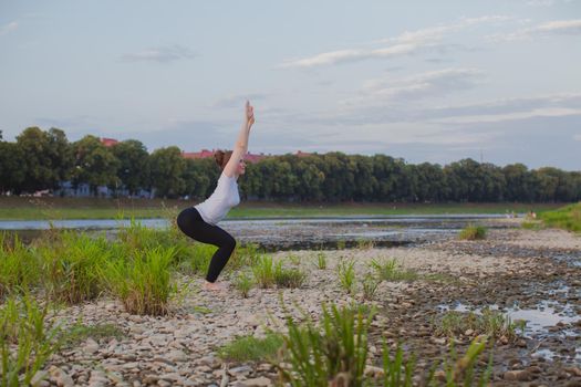 Young woman does yoga on rocks in nature