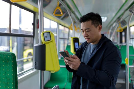 Happy and successful asian male passenger in public transport bought a ticket using a mobile phone