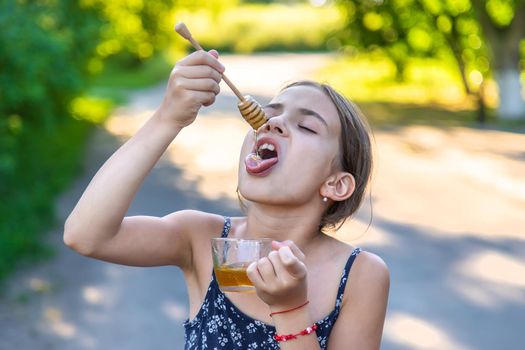 A child eats honey in the park. Selective focus.