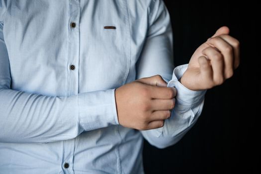 Man businessman buttoning a button on the sleeve of a white dress shirt