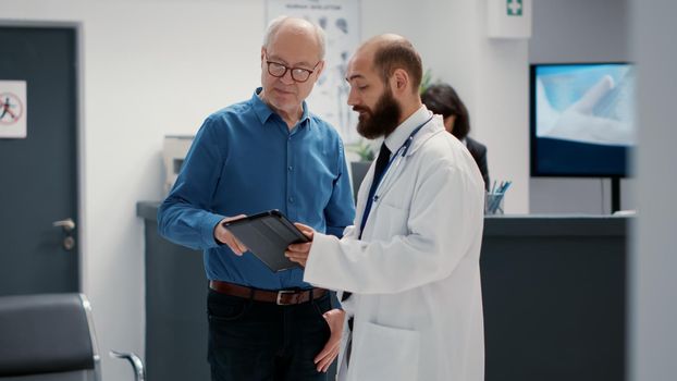 Male physician doing consultation with retired man in hospital reception