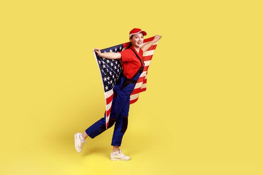 Happy positive worker woman posing with american flag in hands, celebrating patriotic holiday.