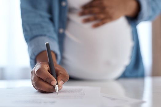Making sure everything is in order before going into labour. a pregnant woman signing documents.