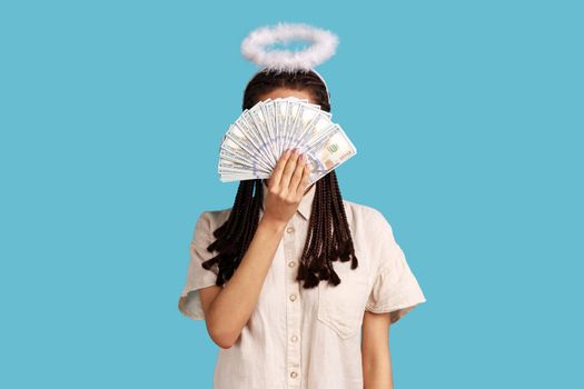 Woman with dreadlocks and nimbus on head hiding behind dollar banknotes, big profit earning cash.