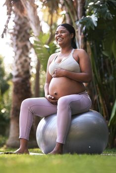 My baby is just as active as I am. a pregnant woman sitting on a stability ball outside.