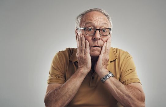 It cant be true. Studio shot of an elderly man in disbelief against a grey background.