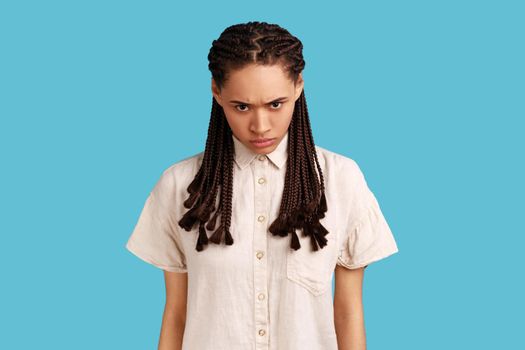 Aggressive woman with black dreadlocks, having irritation squints face, being annoyed with something