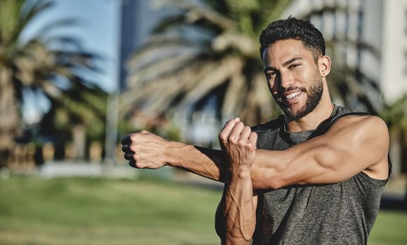 Always start with a stretch. Portrait of a sporty young man stretching his arms while exercising outdoors.