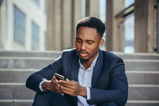 Depressed african american businessman reading bad news from cellphone