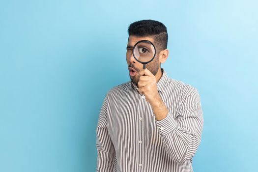 Man holding magnifying glass and looking at camera with big zoom eye, verifying authenticity.