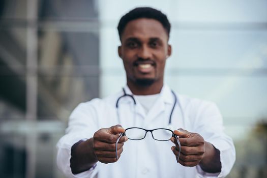 African ophthalmologist doctor offers glasses looking into the camera