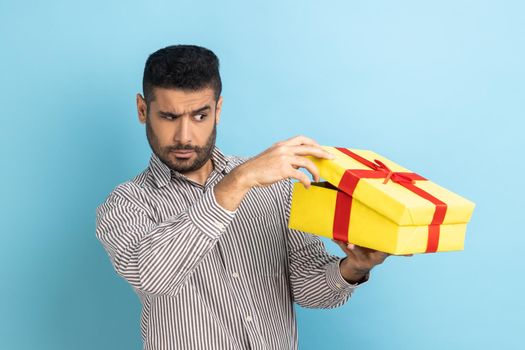 Man look inside gift box, unpacking present to know what he received, frustrated with content.