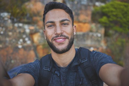 I love taking photos outdoors. a young man taking a break while hiking to snap a quick selfie.